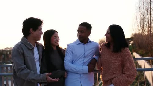 Smiling Friends Chatting on Bridge at Sunset