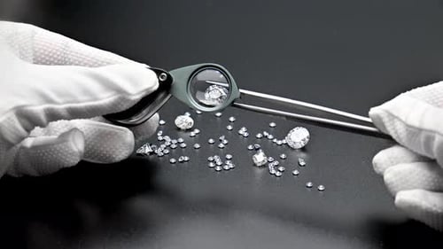 Gemologist inspecting loose diamonds under magnifier