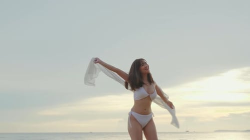 woman wear bikini swimsuit with blowing sarong enjoying walking and spin body at beach