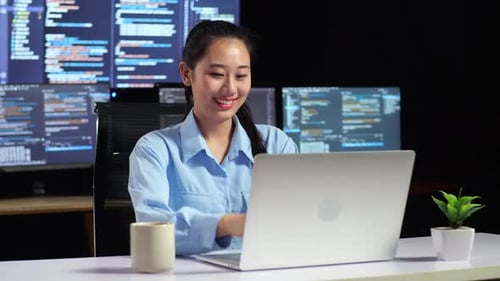 Female Programmer Walking Into The Working Space To Write Code By A Laptop Using Multiple Monitors