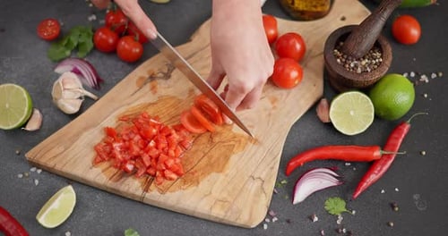 Hands Cutting Tomatoes on a Wooden Board