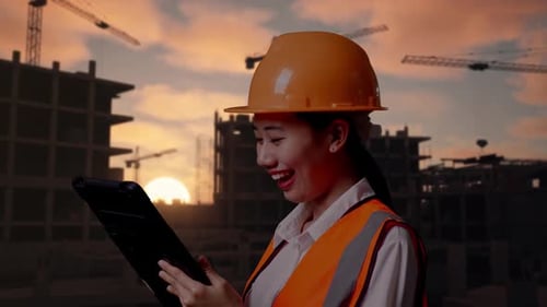 Close Up Side View Of Asian Female Engineer Working On A Tablet At Building Site