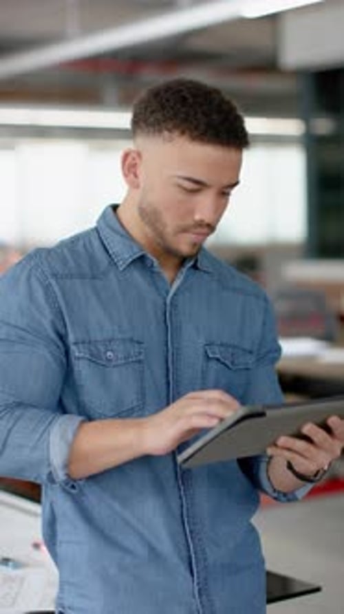 Vertical video of portrait of happy biracial businessman using digital tablet at office