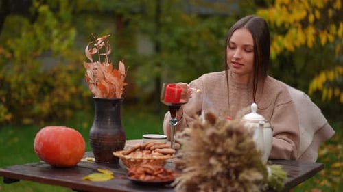 Woman Lights Candle at Outdoor Autumn Tea Table