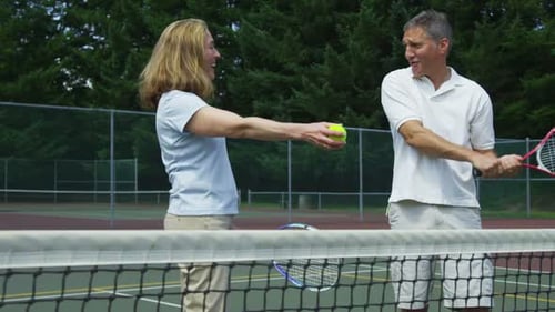 Mature Couple Prepare to Play Tennis 50-55