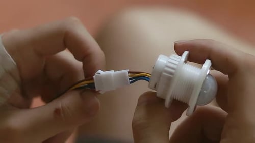 Close up hands assembling and checking the components of a motion sensor bulb