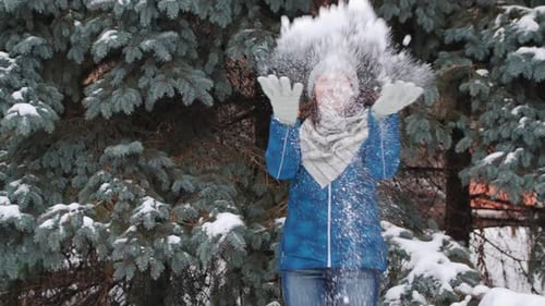 Woman Tossing Snow in Snowy Winter Landscape