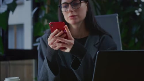 A Girl in Office Holds a Smartphone in Hands Uses Social Media A Business Woman Writes a Message