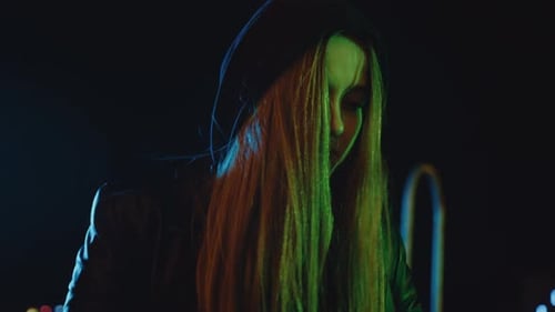 Hooded woman types on laptop outside at night, close-up