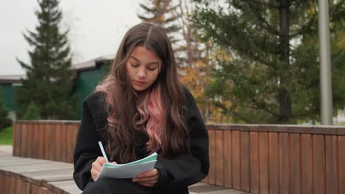 Young Person Studies on Bench in Autumn Park Environment Teenage Learner Pauses Thoughtfully to