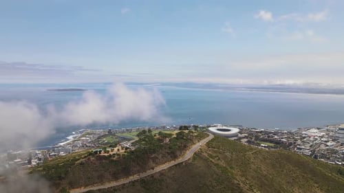 Small clouds above the signal hill and the Cape Town city stadium visible in the background