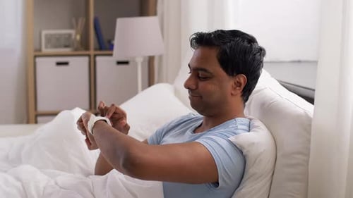 Man in Bed Checks Smartwatch After Waking Up