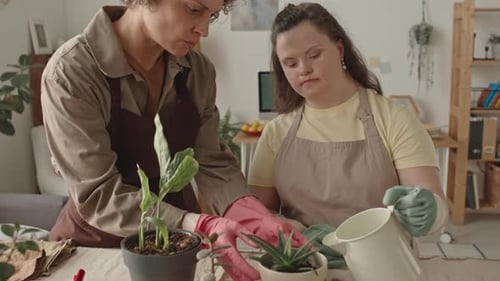 Girl with Down Syndrome Watering Potted Plant with Mom at Home