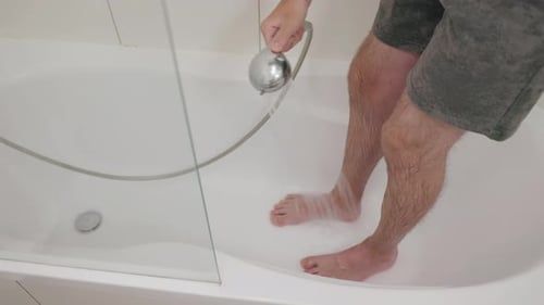 Man Washing His Feet Under a Shower Stream in a Bathtub Closeup of Legs and Running Water Daily