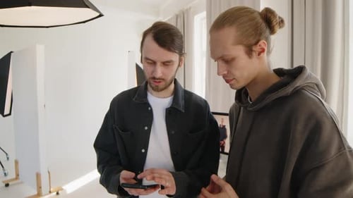 Photographe et assistant discutant pendant une séance photo en studio