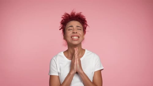 Woman Praying with Hands Together on Pink Background