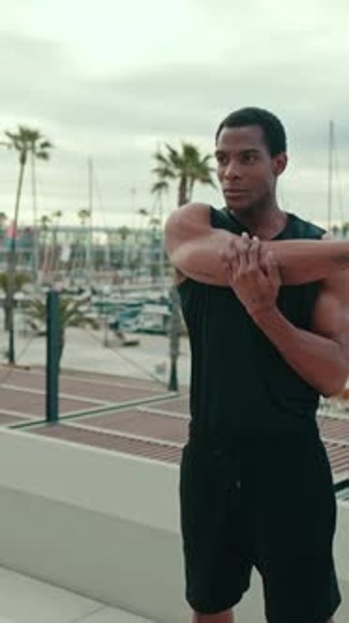 Vertical video, Young Man Stretching by the Marina