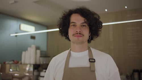 Cheerful Barista Smiling Behind Coffee Shop Counter