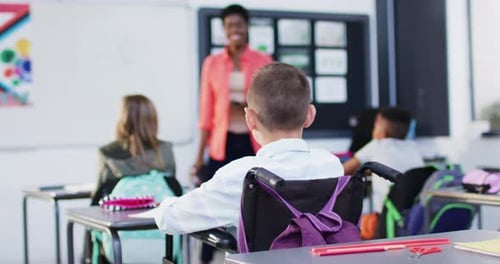 Young Student in Wheelchair Raises Hand in Class