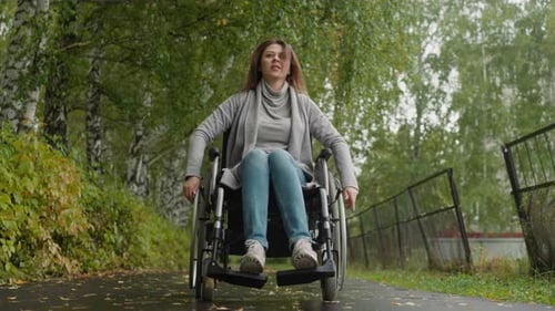 Woman in Wheelchair Walks in Sanatorium Park During Recovery