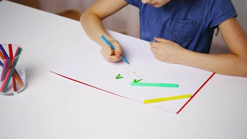 Young Girl Drawing Pictures with Markers on Table