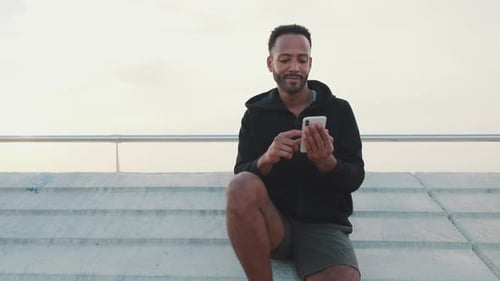 Young Adult Using Mobile Phone on Concrete Stairs