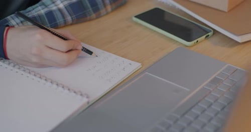 Closeup of Male Hand Writing in Notebook While Kid Doing Mathematics Homework and Studying at Home