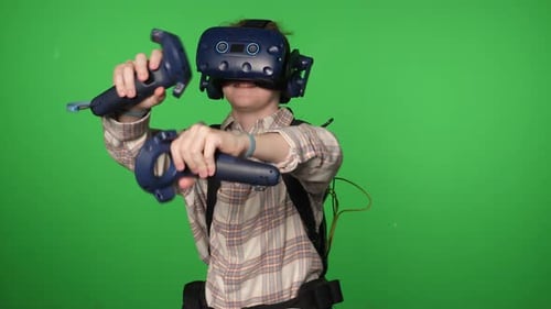 A Boy in Virtual Reality Headset is Playing a Video Game on a Green Background