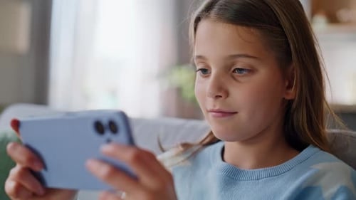 Smiling Girl Plays Game on Smartphone, Indoors