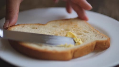 Close Up of Woman Hands Spreading Butter on Toast