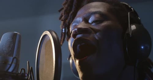 Close Up Portrait of Young Male Black Singer with Headphones Recording an Album in Profes