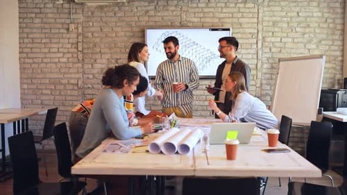 Group of young business people discussing architectural designs in office.