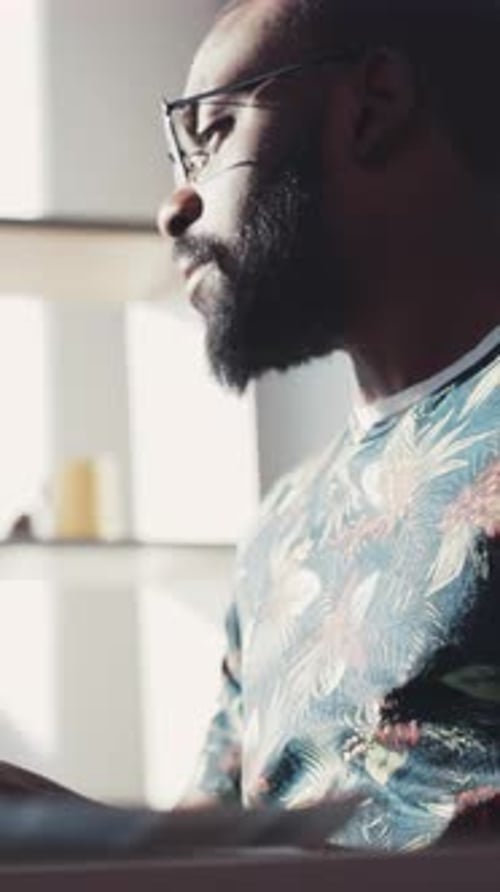 A Thoughtful Man Wearing a Colorful Floral Shirt and Stylish Glasses Deep in Reflection