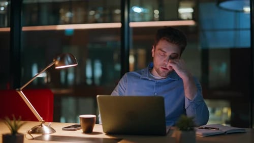 Thoughtful Man Works Late at Office Laptop