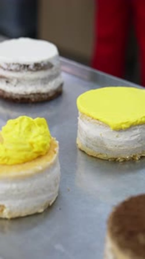 Delicious cakes making in bakery. Pastry chef cooking sweet dessert. Vertical video