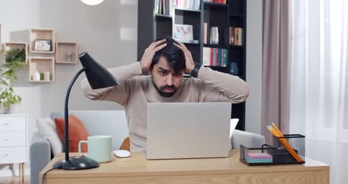 Man Working on Laptop with Shocked Expression