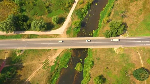 aerial drone shoot. Flying over a bridge green field in a rural landscape. Top view of trees in fore