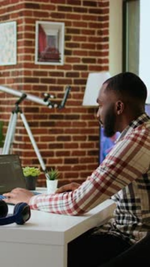 Vertikales Video Afroamerikanischer Softwareentwickler arbeitet an Programmiercode auf einem Laptop