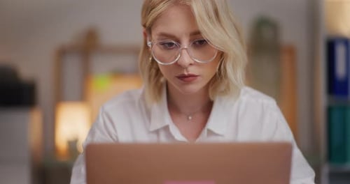 Woman Works on Laptop at Desk Indoors