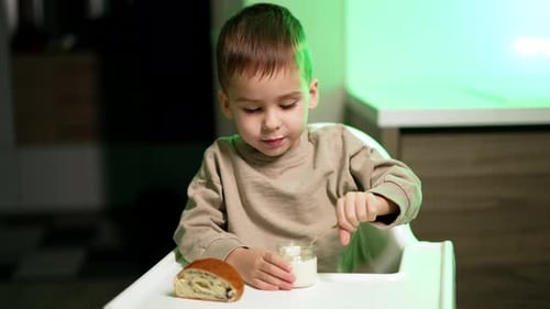 Happy Boy Eats Yogurt at Table Indoors