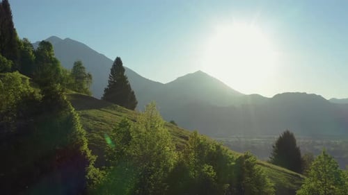 Wide aerial view of an athletic man pedalling an MTB E-bike up a steep grassy hill.
