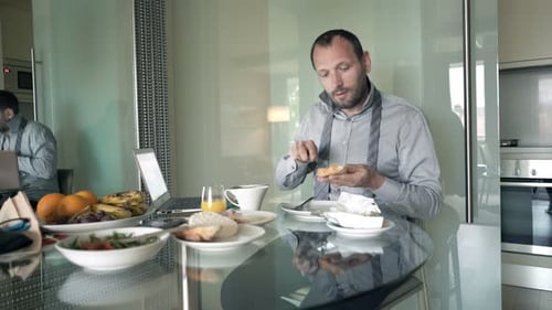 Businessman Preparing Breakfast Sitting By Table At Home