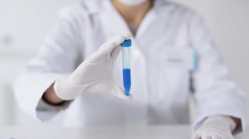 Scientist Holds Vial of Blue Liquid Close Up