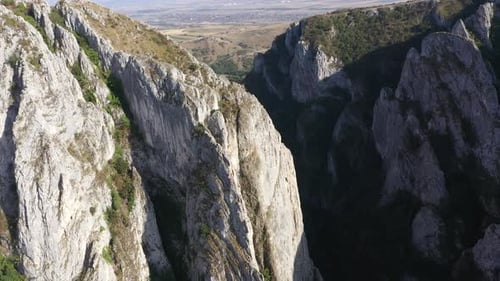 Flying through vertical limestone walls in a deep gorge, canyon, rock climbing aerial
