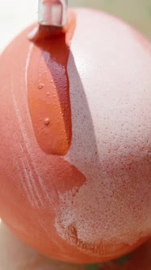 Vertical video. Close-up of a hand painting an Easter egg with a fine brush, creating a perfect,