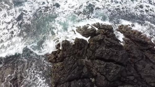 aerial view of waves crashing on shore rocks