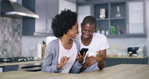 Couple Laughing at Smartphone in Modern Kitchen