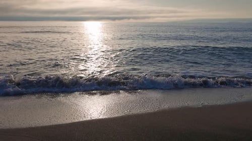 Black Sea and Beach Nearby Against a Sky with Clouds and a Dawn Sun
