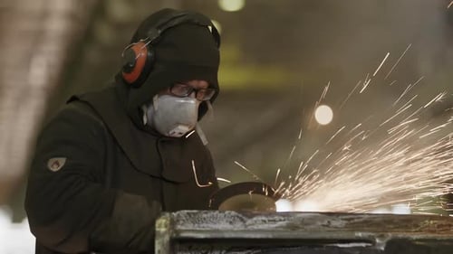 An Industrial Worker Operates a Grinder Inside a Workshop Environment with Focus and Skill Stock