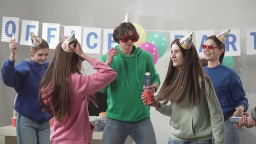 A Group of Colleagues in Festive Hats and Glasses are Dancing Having Fun Celebrating a Common
